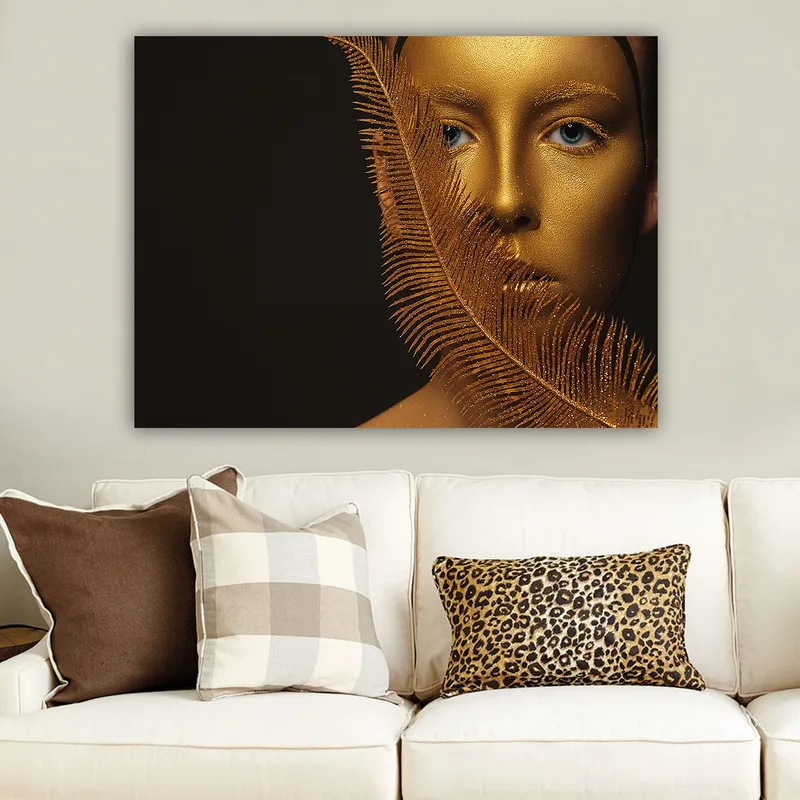 Canvastavla 70x100 cm - Ansiktsporträtt med en gyllene yta och blå ögon, omgiven av en dekorativ fjäderliknande struktur, Guld / Blå