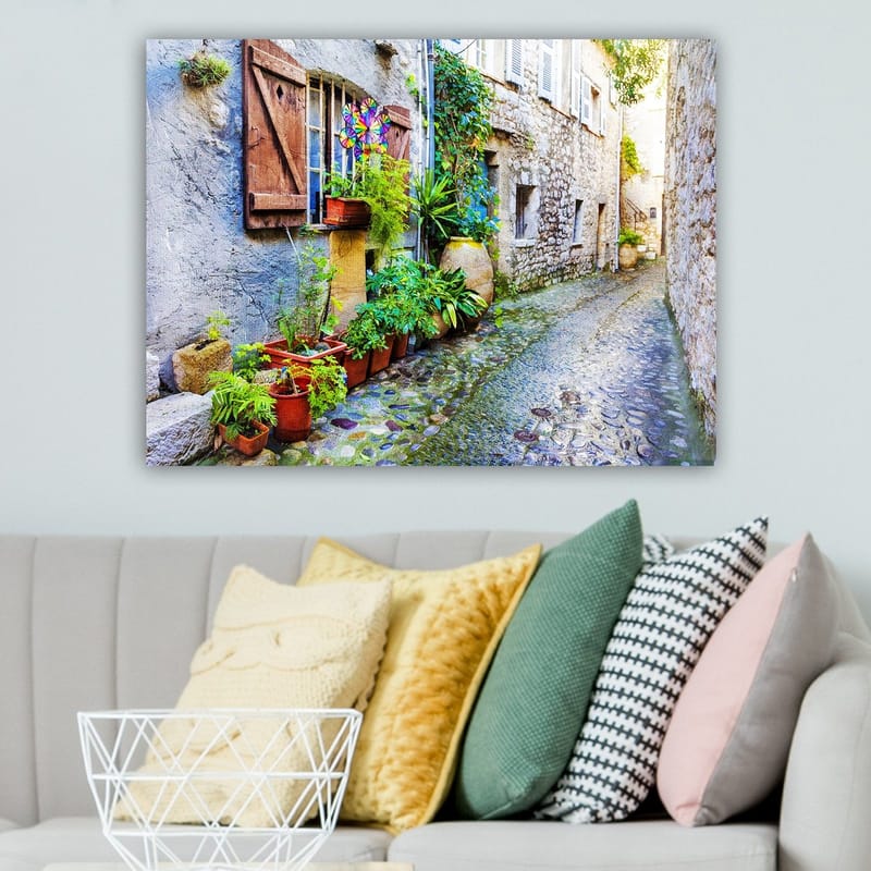 Canvastavla 70x100 cm - Charmig gränd med stenhus och blomsterkrukor som skapar en livlig atmosfär - Grön / Blå / Beige - Inredning - Tavlor & konst - Canvastavlor