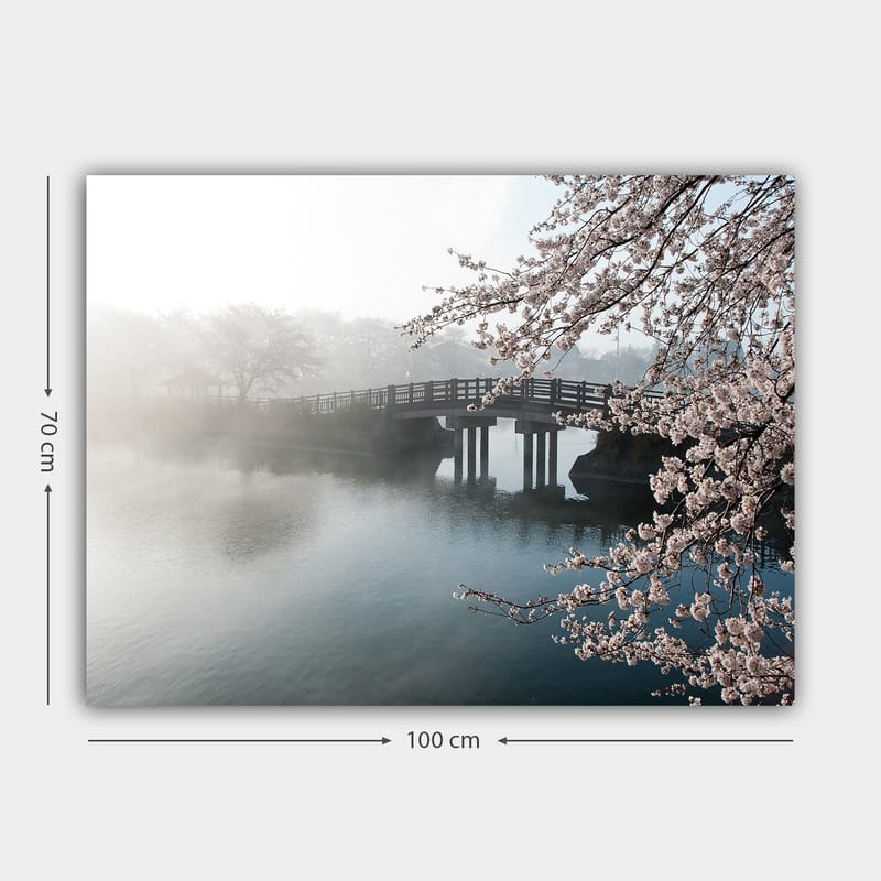 Canvastavla 70x100 cm - Dimmig scen med en bro som sträcker sig över en stilla sjö, omgiven av körsbärsträd i blom - Ljusrosa / Blå / Grå - Inredning - Tavlor & konst - Canvastavlor