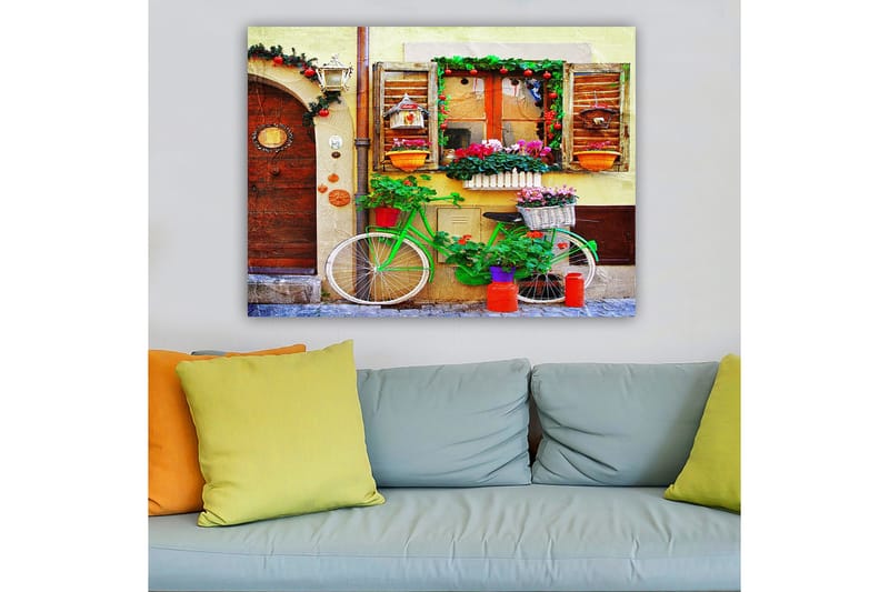 Canvastavla 70x100 cm - Färgglad cykel prydd med blommor och krukor framför en charmig vägg med fönster och dekorationer - Grön / Rosa / Orange - Inredning - Tavlor & konst - Canvastavlor