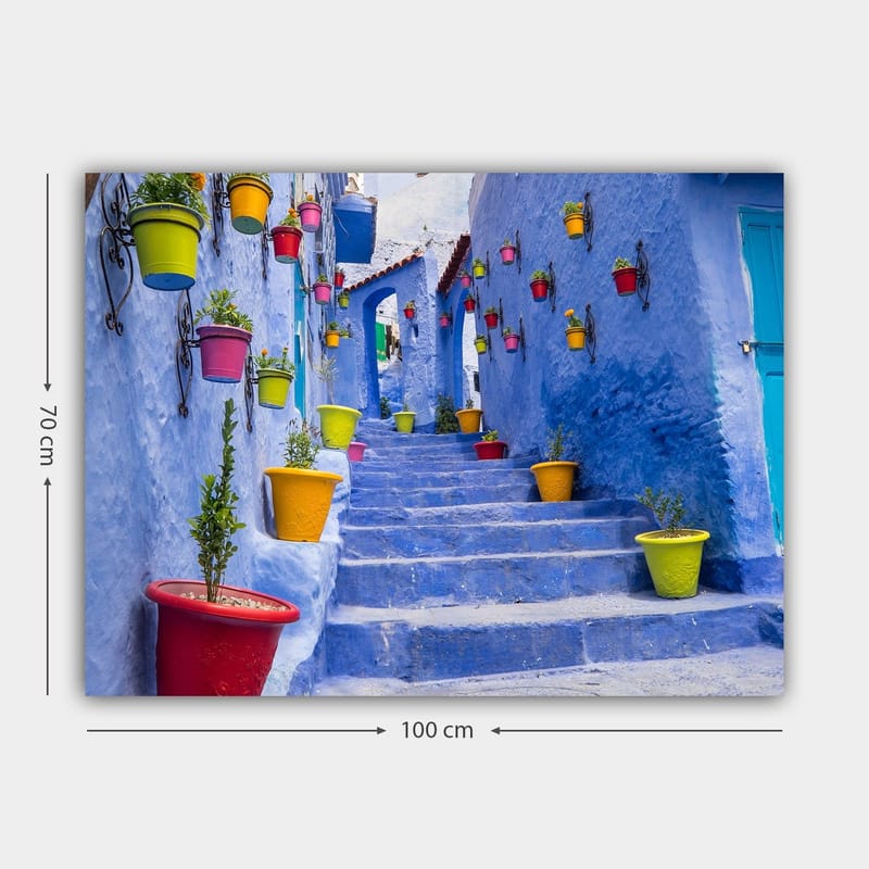 Canvastavla 70x100 cm - Färgglad trappa omgiven av blomkrukor i en pittoresk, blå stadsmiljö - Blå / Gul / Röd - Inredning - Tavlor & konst - Canvastavlor