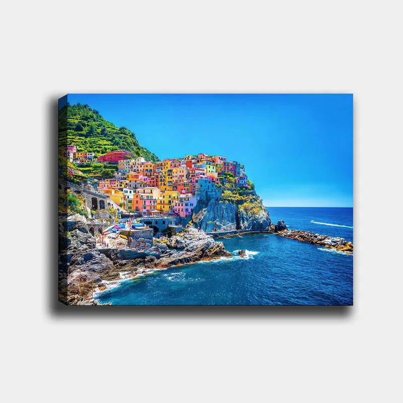 Canvastavla 70x100 cm - Färgglada hus som klättrar uppför en klippa vid havet, Blå / Gul / Rosa