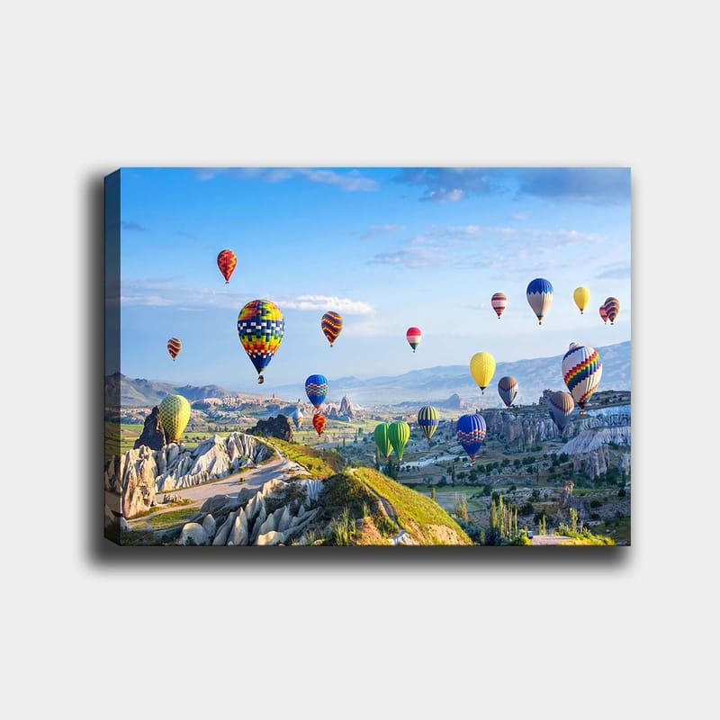 Canvastavla 70x100 cm - Färgglada varmluftsballonger sväva över en vacker landskapsscen i Cappadocia, Grön / Blå / Gul