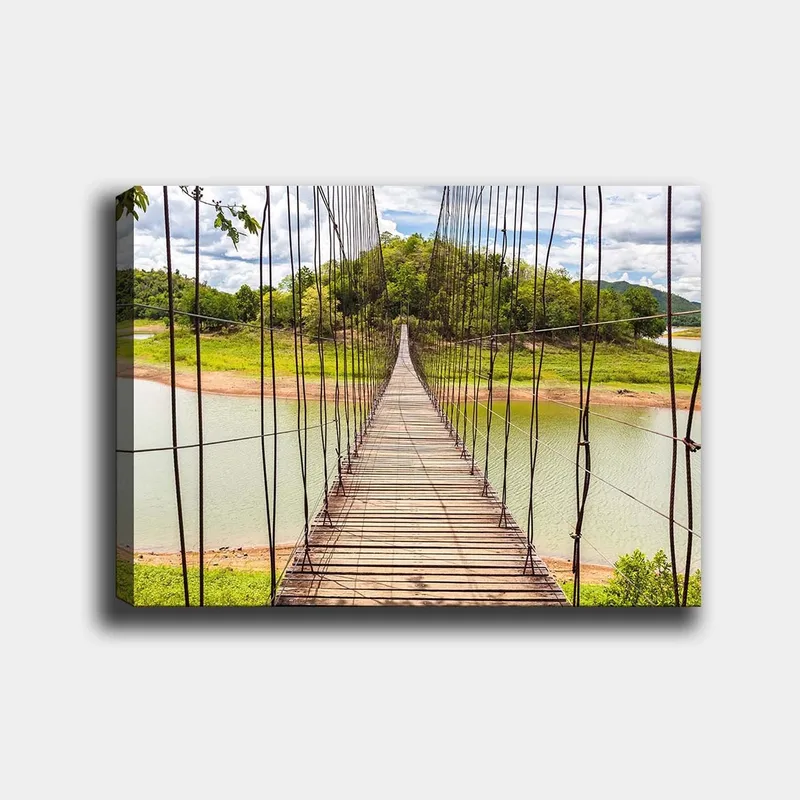 Canvastavla 70x100 cm - Hängbro som sträcker sig över en stilla sjö, omgiven av grönskande landskap, Grön / Brun / Blå