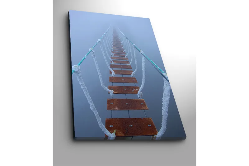 Canvastavla 70x100 cm - Hängbro som sträcker sig genom dimma, vilket skapar en mystisk och avlägsen känsla - Mörkbrun / Vit / Ljusblå - Inredning - Tavlor & konst - Canvastavlor