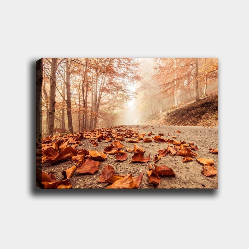 Canvastavla 70x100 cm - Höstig väg kantad av fallna, bruna löv under träd med gyllene och orangea lövverk, Orange / Brun