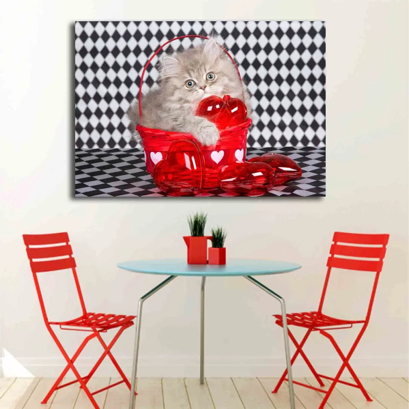 Canvastavla 70x100 cm - Kattunge som sitter i en röd korg fylld med hjärtformade dekorationer - Röd / Grå - Inredning - Tavlor & konst - Canvastavlor