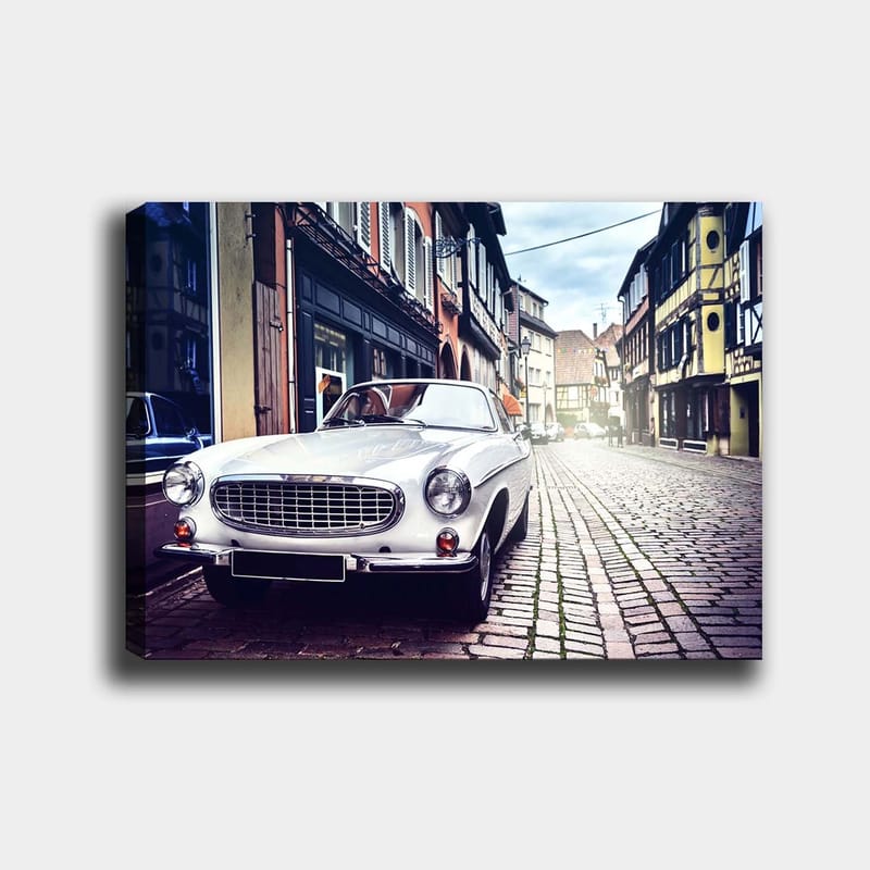 Canvastavla 70x100 cm - Klassisk vit bil parkerad på en charmig, gammaldags gata med historiska byggnader, Vit / Svart / Grå