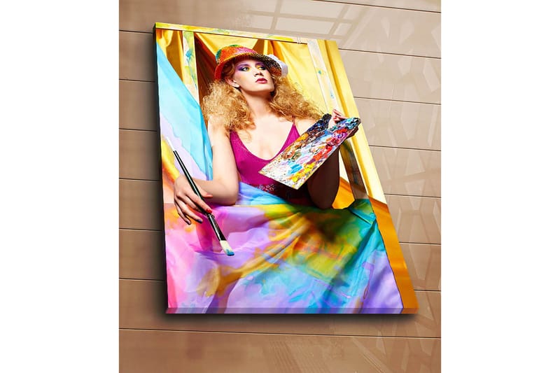 Canvastavla 70x100 cm - Kreativ kvinna som målar med en palett i handen, omgiven av färgglada tyger - Rosa / Blå / Gul - Inredning - Tavlor & konst - Canvastavlor