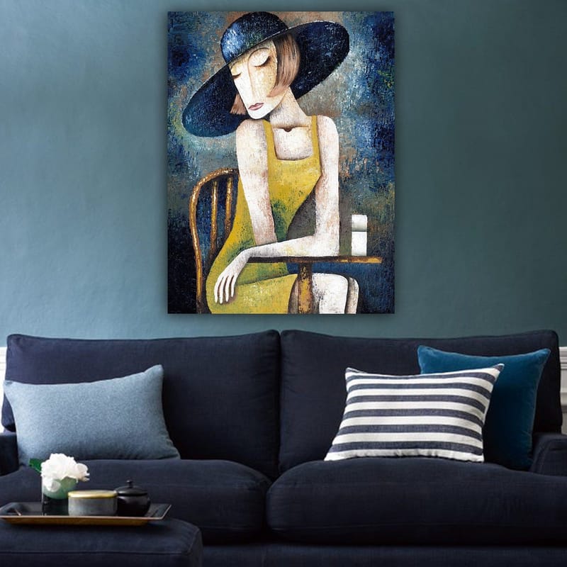 Canvastavla 70x100 cm - Kvinna i en gul klänning sitter vid ett bord med en vit kopp, iförd en stor svart hatt - Gul / Svart / Blågrön - Inredning - Tavlor & konst - Canvastavlor