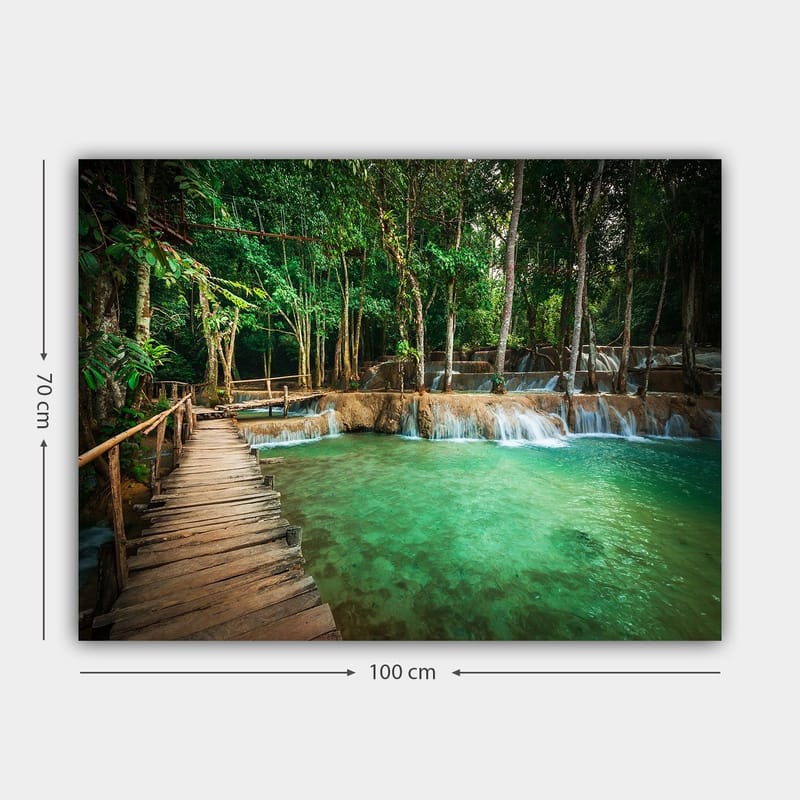 Canvastavla 70x100 cm - Lugn och naturskön plats med en träbro som leder över en klar, turkos vattenfallspool omgiven av frodig grönska - Turkos / Grön / Brun - Inredning - Tavlor & konst - Canvastavlor