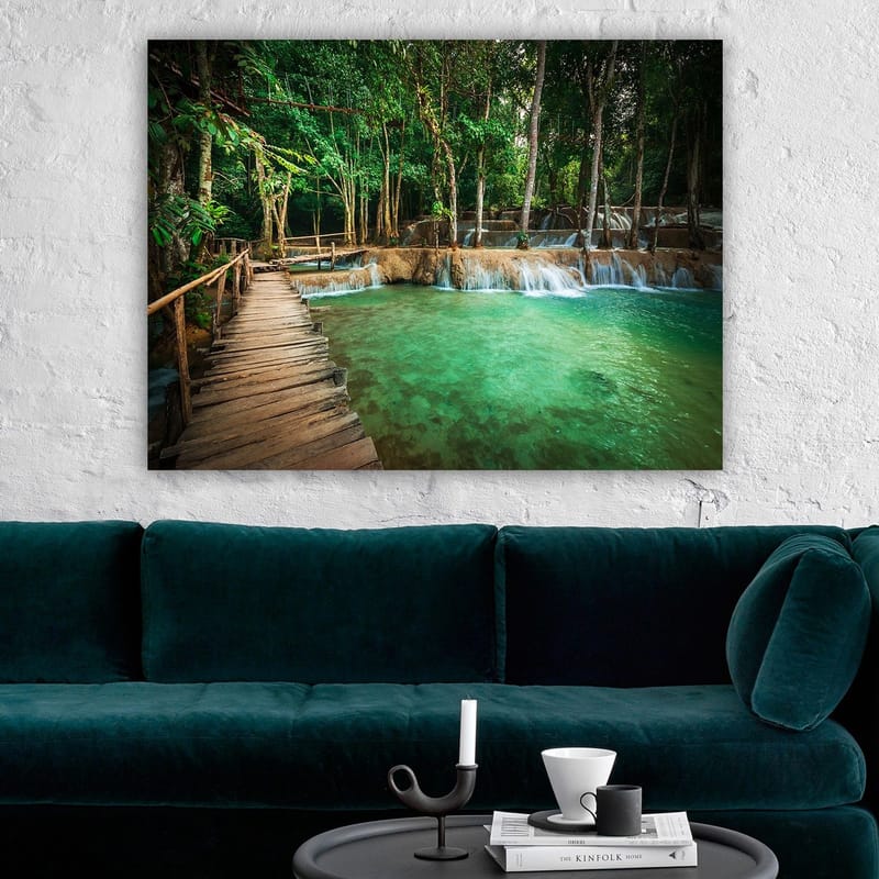 Canvastavla 70x100 cm - Lugn och naturskön plats med en träbro som leder över en klar, turkos vattenfallspool omgiven av frodig grönska - Turkos / Grön / Brun - Inredning - Tavlor & konst - Canvastavlor