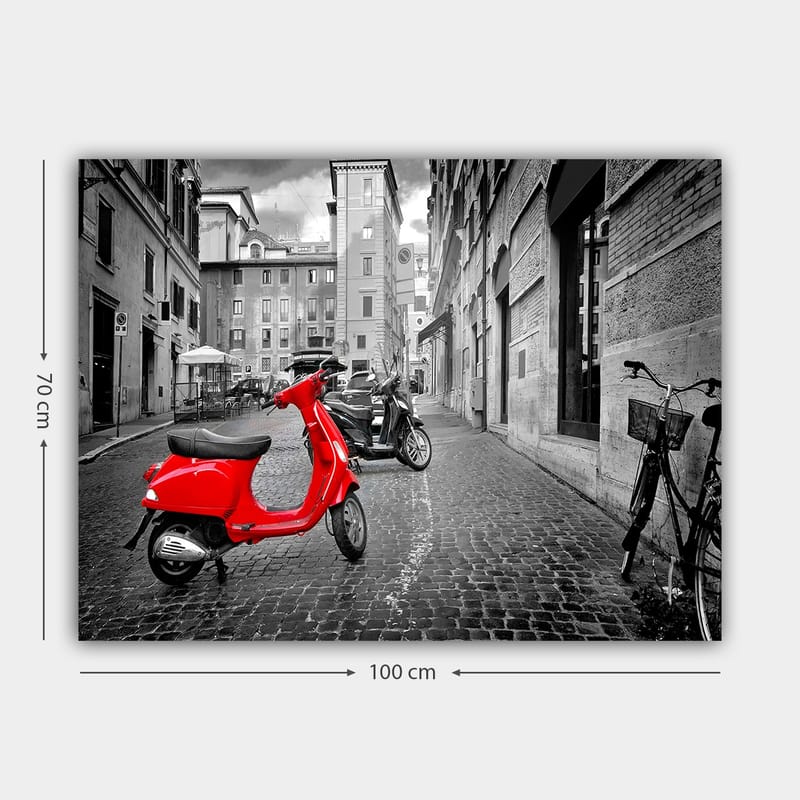 Canvastavla 70x100 cm - Röd scooter står i en svartvit stadsmiljö med kullerstensgator och byggnader - Röd / Svart / Grå - Inredning - Tavlor & konst - Canvastavlor