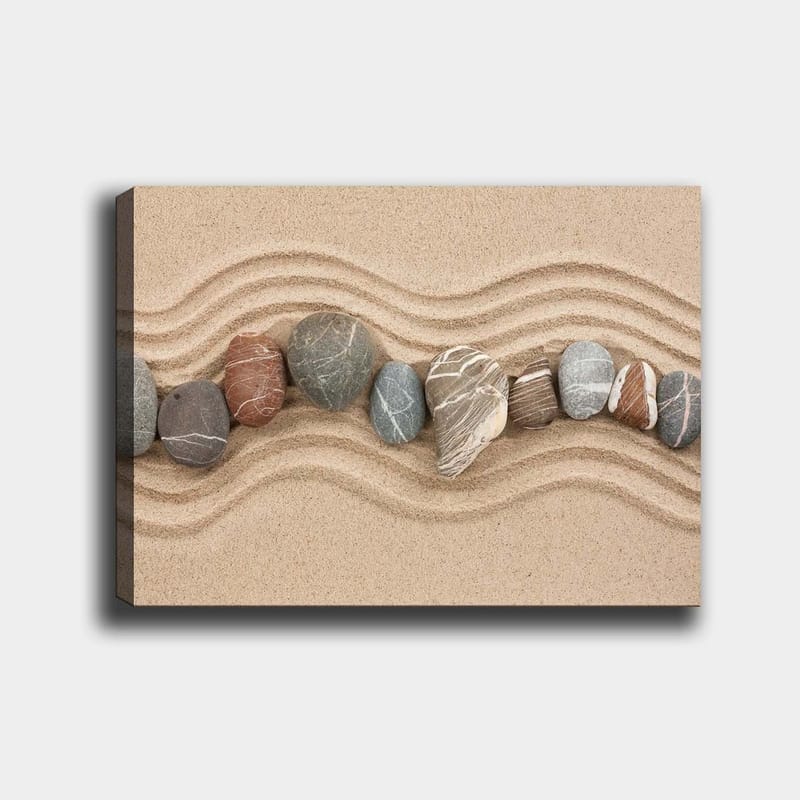Canvastavla 70x100 cm - Rad av släta stenar placerade på en sandig yta med vågiga mönster, Sandbeige / Grå / Rödbrun