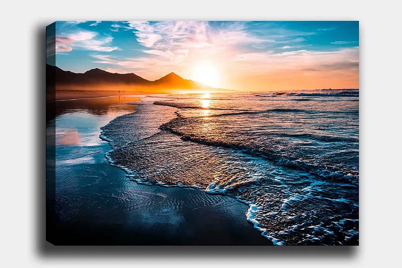 Canvastavla 70x100 cm - Solnedgång över en strand med mjuka vågor som rullar in mot kusten, Blå / Orange / Turkos