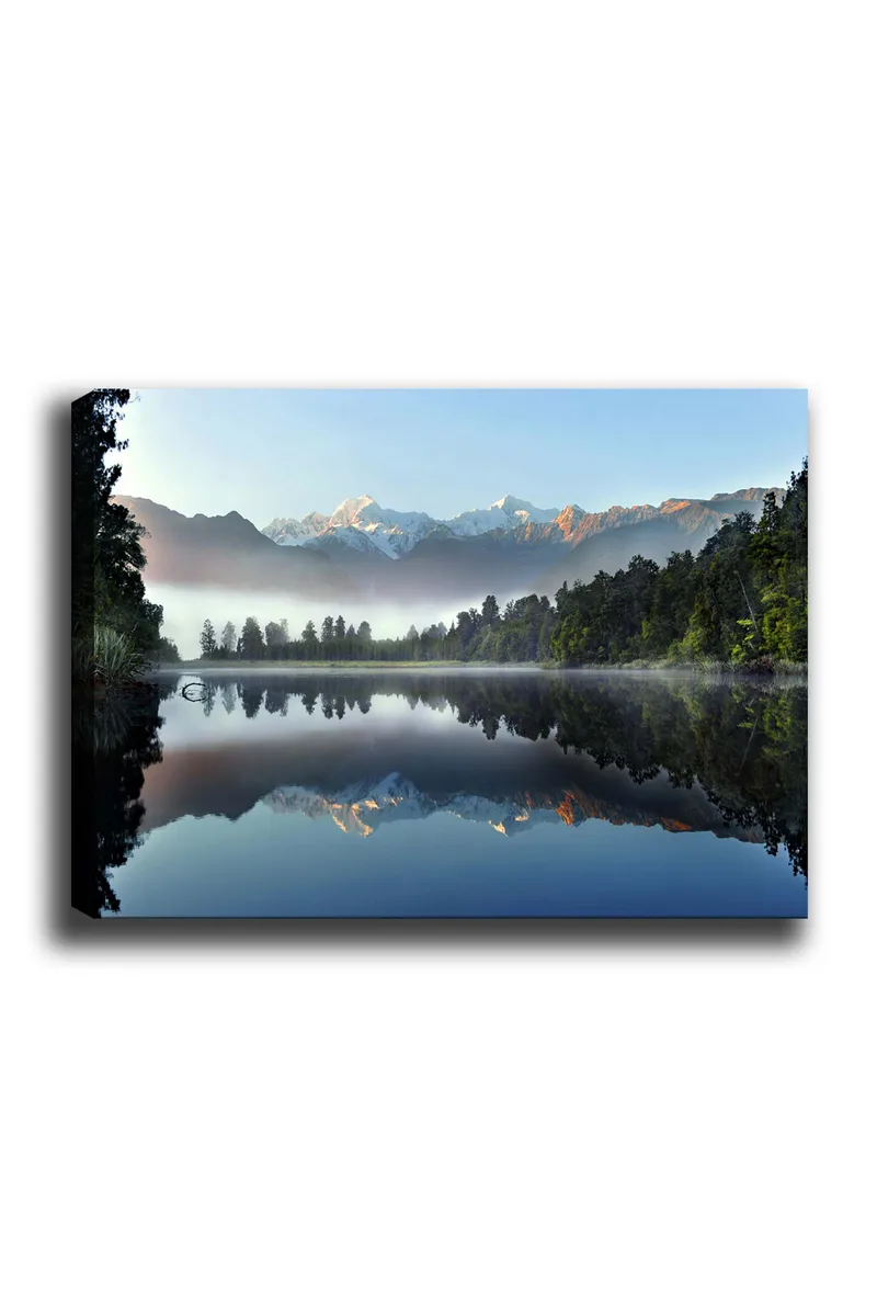 Canvastavla 70x100 cm - Spegelbild av majestätiska berg som reflekteras i en stilla sjö omgiven av grönskande skog, Blå / Grön / Vit