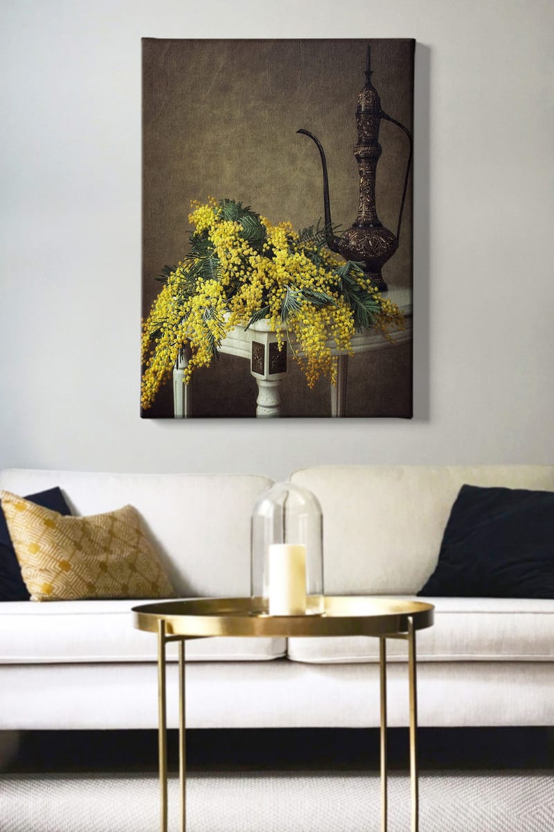 Canvastavla 70x100 cm - Vacker bukett av mimosa blommor i gult, placerad på ett bord bredvid en elegant, mörkbrun kanna - Gult / Mörkgrönt / Brunt - Inredning - Tavlor & konst - Canvastavlor