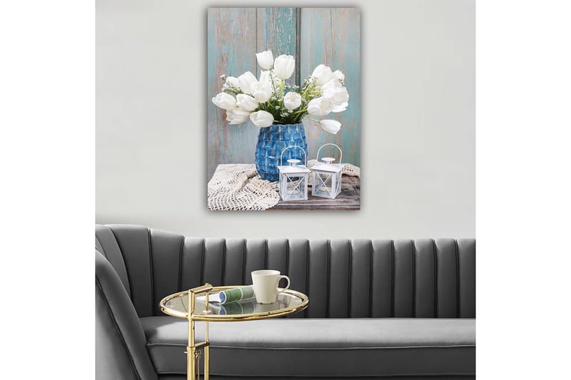 Canvastavla 70x100 cm - Vacker bukett vita tulpaner i en blå vas, placerad på en träyta med ljusa detaljer, Vit / Blå / Grå