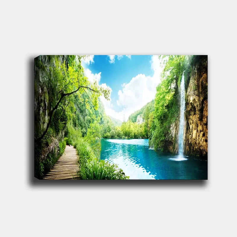 Canvastavla 70x100 cm - Vacker naturscen med en vattenfall som rinner ner i en klar, blå sjö omgiven av frodig grönska och berg - Grön / Blå - Inredning - Tavlor & konst - Canvastavlor