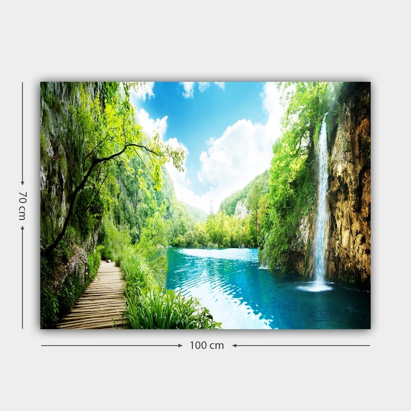 Canvastavla 70x100 cm - Vacker naturscen med en vattenfall som rinner ner i en klar, blå sjö omgiven av frodig grönska och berg - Grön / Blå - Inredning - Tavlor & konst - Canvastavlor