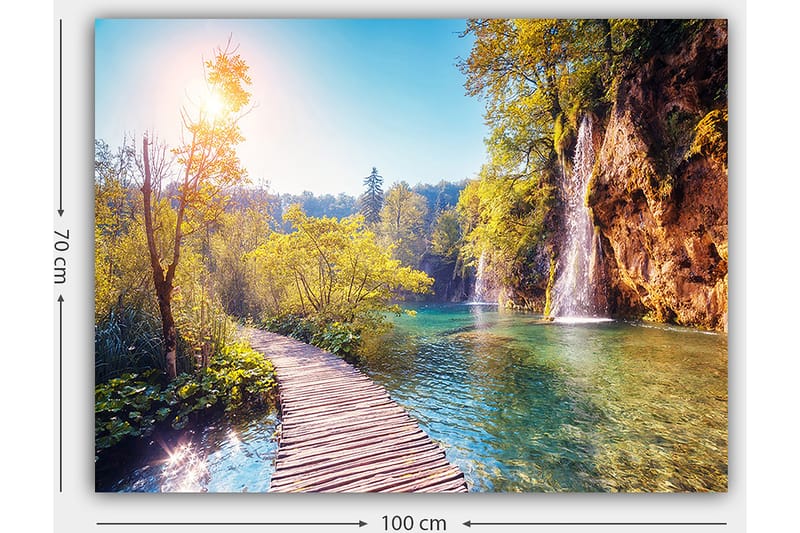 Canvastavla 70x100 cm - Vacker naturvy med en träbro som leder genom grönskande landskap och en vattenfall i bakgrunden - Grön / Blå / Gul - Inredning - Tavlor & konst - Canvastavlor