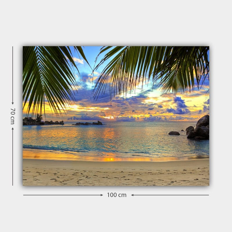 Canvastavla 70x100 cm - Vacker solnedgång över en strand med palmer som ramar in motivet - Blå / Orange / Grön - Inredning - Tavlor & konst - Canvastavlor