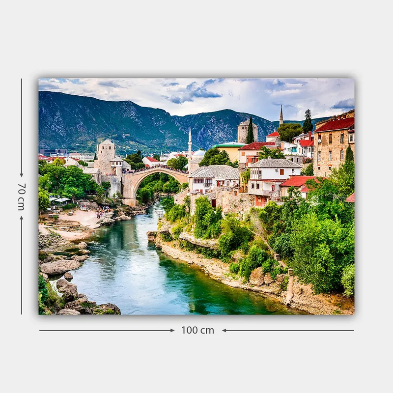 Canvastavla 70x100 cm - Vacker vy över en historisk bro som sträcker sig över en flod, omgiven av pittoreska hus och grönskande landskap - Grön / Blå / Röd - Inredning - Tavlor & konst - Canvastavlor