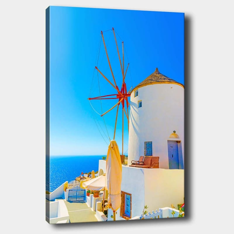 Canvastavla 70x100 cm - Vit vindmölla med röd rotor på en klippa vid havet, omgiven av klarblå himmel och hav, Vit / Röd / Blå