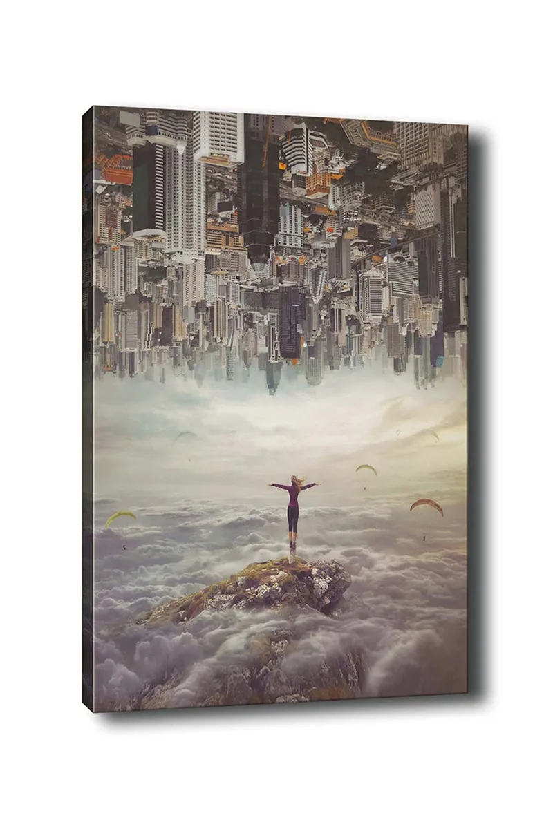 Canvastavla 70x100 cm - Person står med utsträckta armar på en klippa ovanför molnen, med en stad i bakgrunden som är upp och ner, Grå / Beige / Mörkblå
