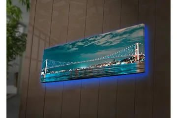 Canvastavla med LED-belysning 30x90 cm - Bro över en stilla vattenyta med stadsljus i bakgrunden - Mörkblå / Turkos / Ljusgrön - Inredning - Tavlor & konst - Canvastavlor