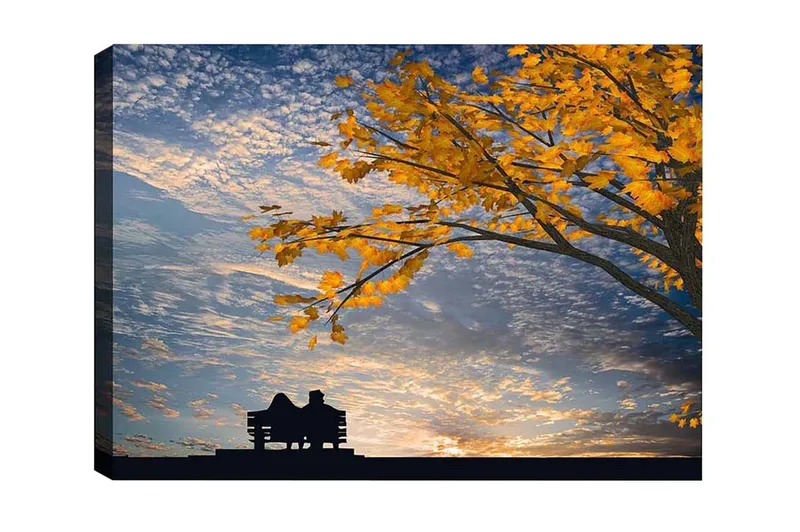 Canvastavla - Silhuett av ett par som sitter på en bänk under ett träd med gyllene höstlöv, Guld / Blå / Svart